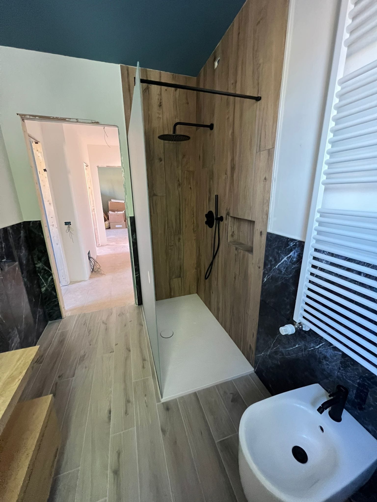 Doccia con rivestimento effetto legno, nicchia portaoggetti e rubinetteria nera