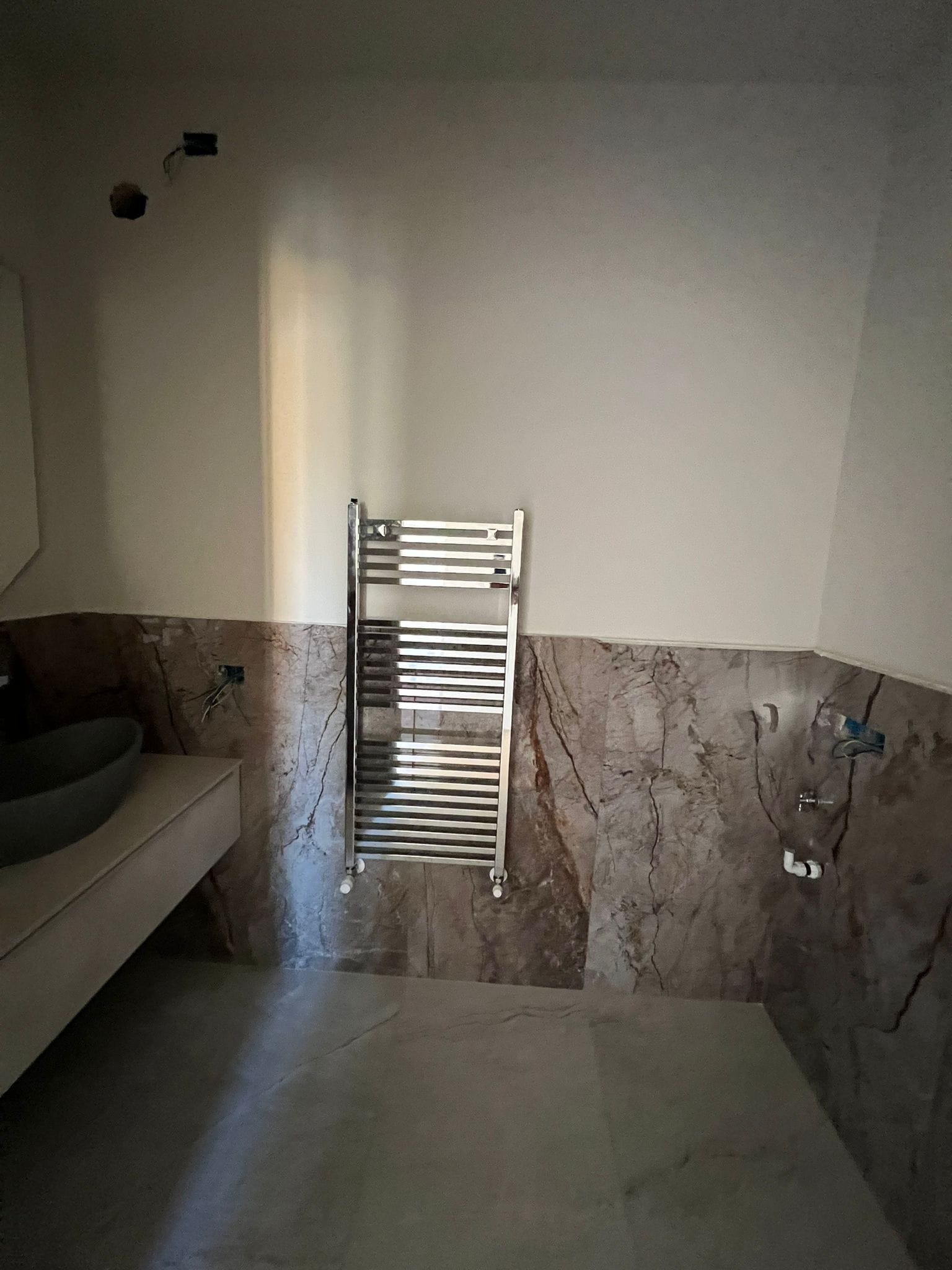 Scaldasalviette cromato su rivestimento in lastre effetto marmo bruno