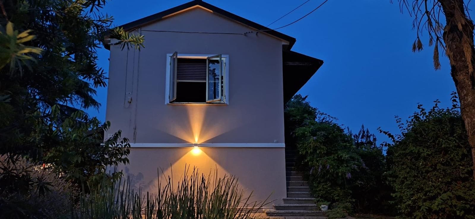 Casa con facciata rifatta e applique luminosa, fotografata al tramonto