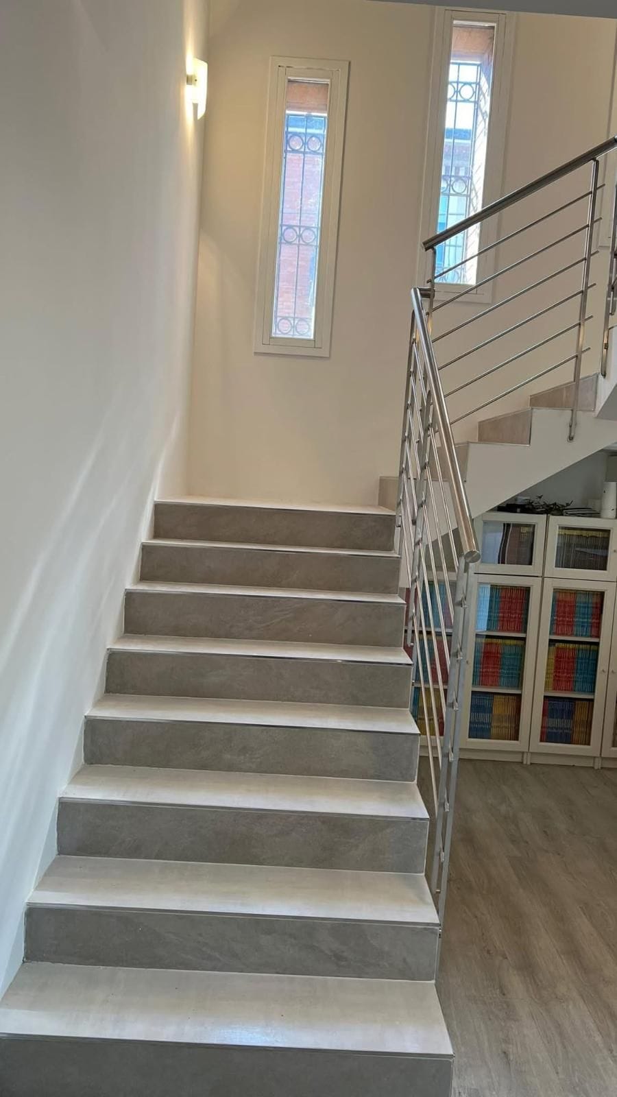 Scala interna rivestita in gres con profili in acciaio e ringhiera inox