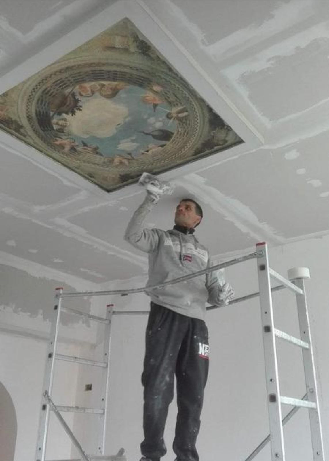 Stuccatura dei giunti di un soffitto in cartongesso con cornice attorno a un pannello dipinto