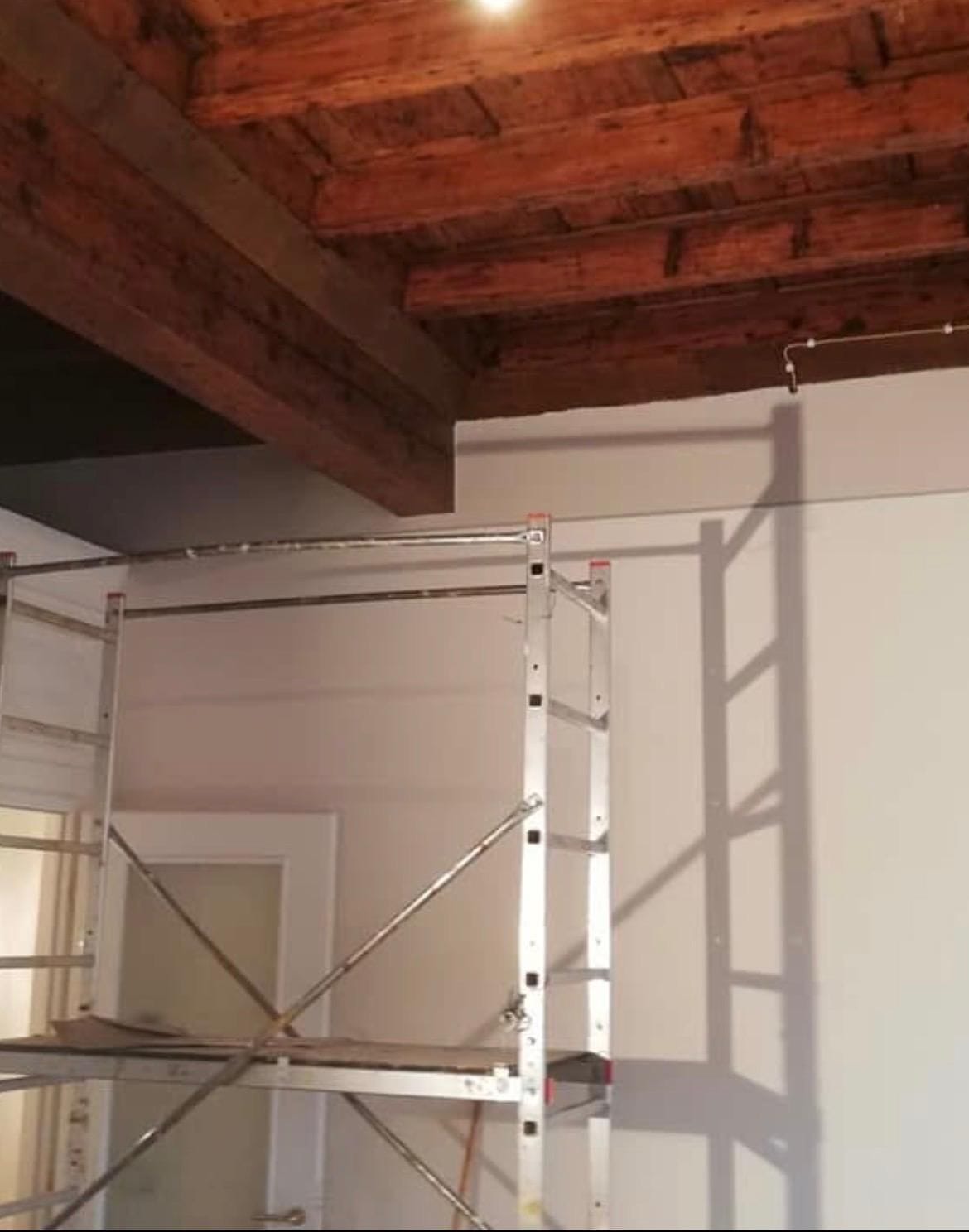 Soffitto a travi in legno recuperato e pareti nuove, con trabattello in cantiere
